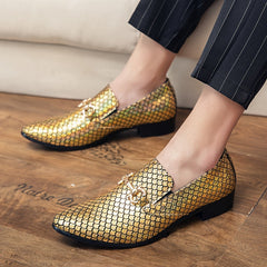 A pair of gold metallic slip-on loafers with a scale pattern and a decorative metal bit.