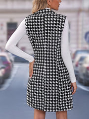 A woman wears a sleeveless black and white houndstooth vest with a lapel collar over a white top.