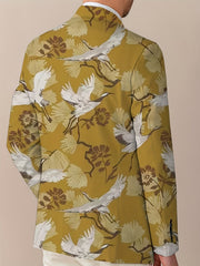 A man wears a mustard yellow blazer featuring a repeating pattern of white cranes and flowers.