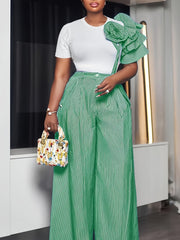 A woman wears a white short-sleeve top with a green striped ruffle shoulder and matching pants.