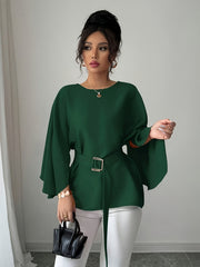 A woman wears a dark green long-sleeve blouse with a belted waist and split sleeves.