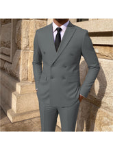 A man wears a grey double-breasted suit with a white shirt and black tie.