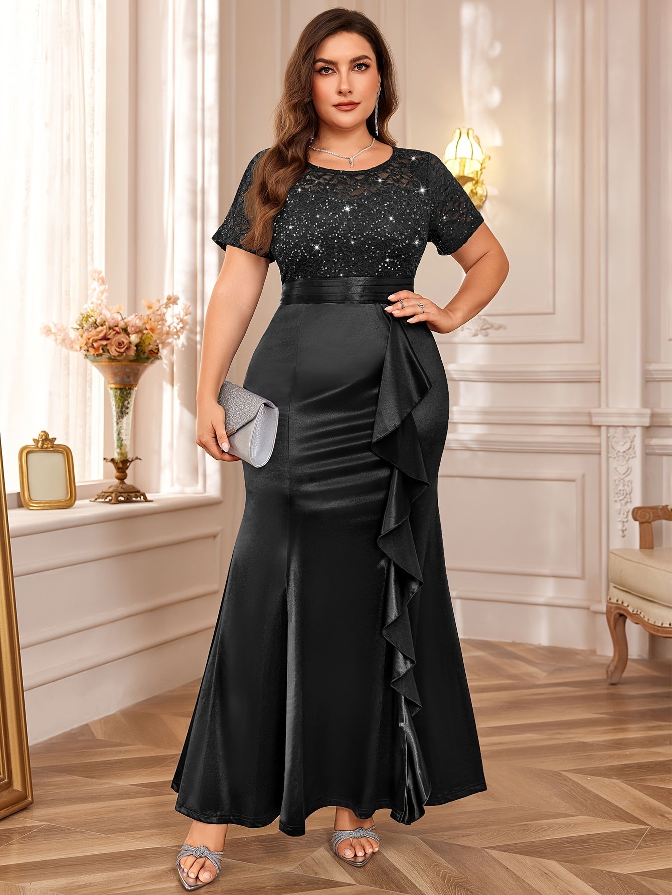 A plus size black floor-length dress with a sequined lace bodice, short sleeves, and a ruffled hem.