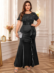 A plus size black floor-length dress with a sequined lace bodice, short sleeves, and a ruffled hem.