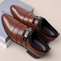 A pair of brown pointed-toe men's business shoes with a buckle strap and black elastic detailing.