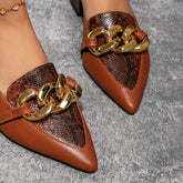 Brown pointed-toe mules featuring a snakeskin-textured panel and a chunky gold-tone chain detail.