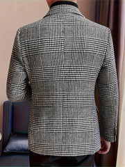 A man wears a black and white houndstooth blazer with a lapel collar and button details.