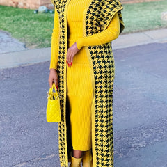 A woman wears a long, yellow and black houndstooth knit cardigan over a matching yellow ribbed dress.
