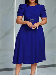 A woman wears a solid blue, short-sleeved A-line dress with a belted waist and puff sleeves.