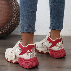 A pair of beige and red chunky sneakers with a thick sole worn with blue jeans.