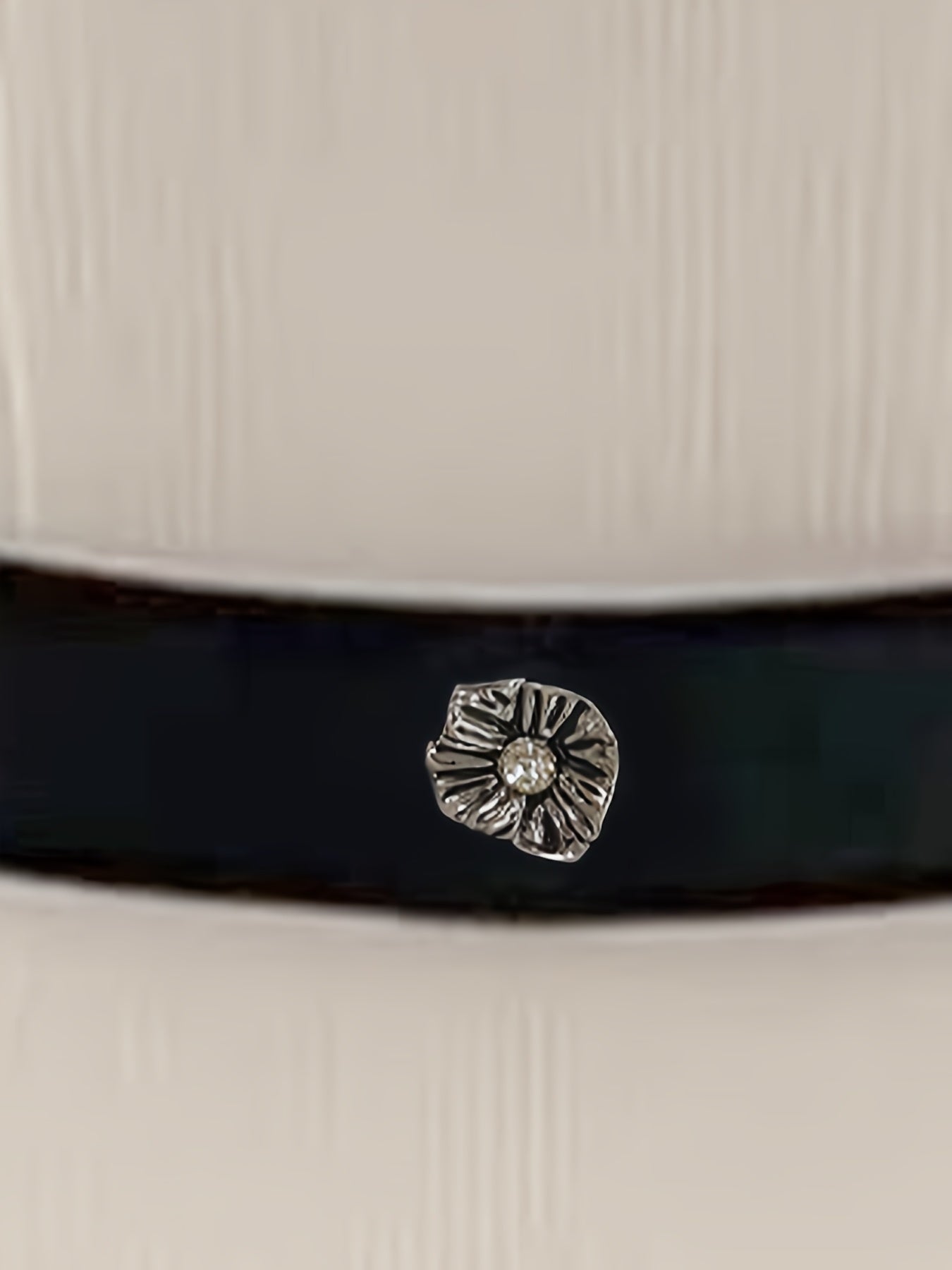 A white blouse featuring a black waist belt adorned with a silver flower-shaped embellishment.