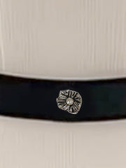 A white blouse featuring a black waist belt adorned with a silver flower-shaped embellishment.