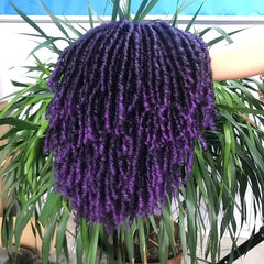 A short purple synthetic dreadlock wig with curly ends held in front of a green plant.
