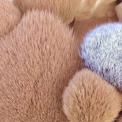 A close-up view of several soft, fluffy makeup brushes with tan and white bristles.