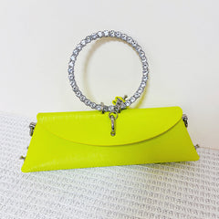 A neon yellow faux leather clutch bag featuring a circular rhinestone-embellished handle.