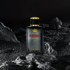 A rectangular black perfume bottle with a gold crown logo and cap sits on dark rocky terrain.