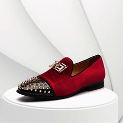 A red velvet loafer with a black patent leather toe cap, gold spikes, and a gold metal buckle.
