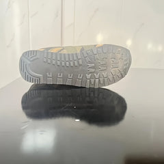 A low-top camouflage sneaker with a textured grey rubber outsole resting on a reflective surface.