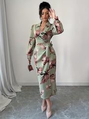A woman wears a sage green midi dress with a floral print, V-neck, and long lantern sleeves.