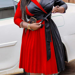 A plus-size V-neck dress featuring a color-blocked red and black pleated skirt with a waist tie.