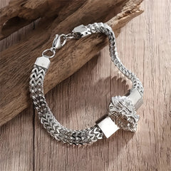 A silver-toned stainless steel bracelet featuring a lion head charm and a braided chain design.