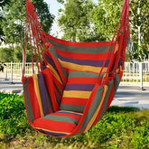 A colorful striped canvas hammock chair with a matching cushion and pillow hanging outdoors.