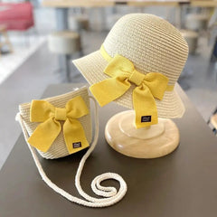 A kids' sun hat and matching straw bag set, both with yellow bows, for ages 2-8. The summer accessory set offers sun protection—perfect for travel or the beach. Displayed on a table with a blurred background.