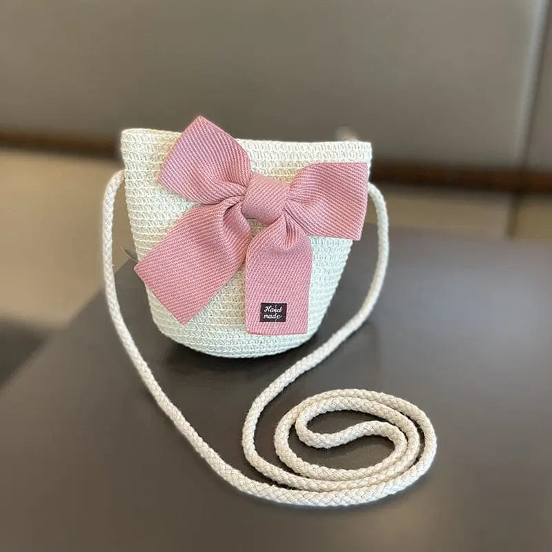 A girls' sun hat and white woven crossbody straw bag set with a pink bow, designed for ages 2-8, is shown on a dark surface. The summer cap is perfect for beach trips and outdoor sun protection for children.