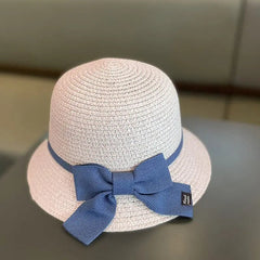 A light beige 2-8 Years Kids Sun Hat with a wide blue ribbon, perfect for summer sun protection, is placed on a dark surface with a blurred background.