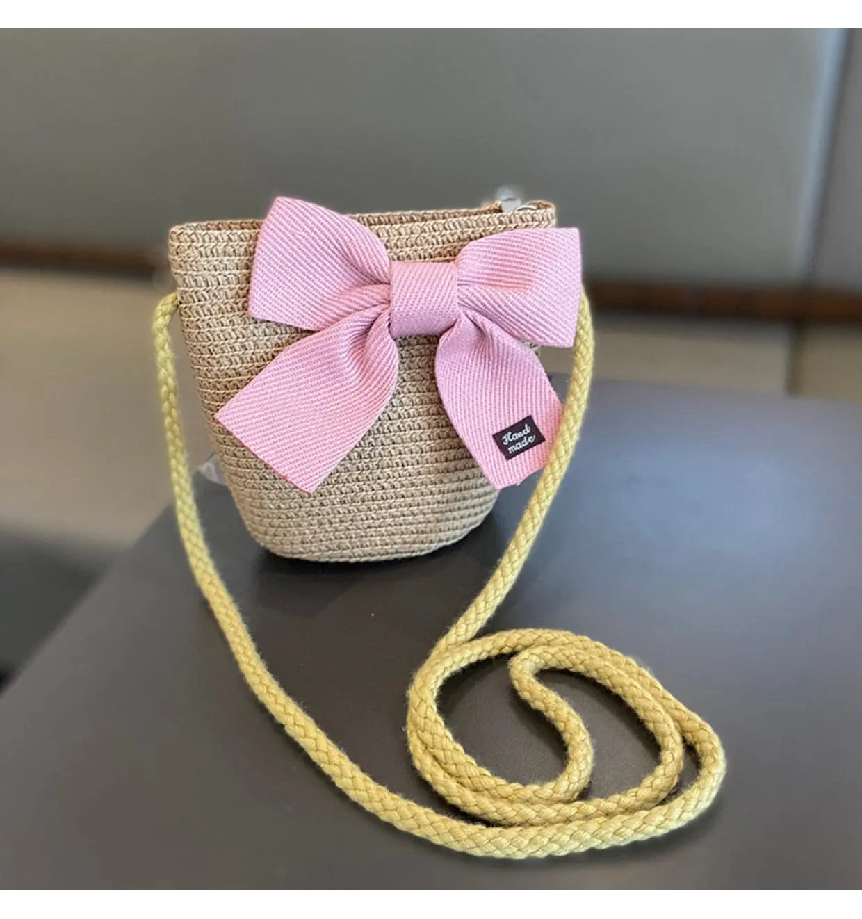 The 2-8 Years Kids Sun Hat Girls Summer New Straw Bag Cap Set features a woven straw purse with a yellow strap and pink bow, reminiscent of a sun hat, perfect for travel or beach outings.