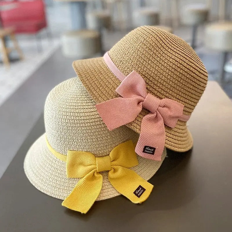 Two straw sun hats for kids (ages 2-8) from the Summer Straw Bag Cap Set—one with a pink ribbon, one with a yellow ribbon—are displayed on a dark surface; perfect beach hats for boys or girls offering stylish sun protection.