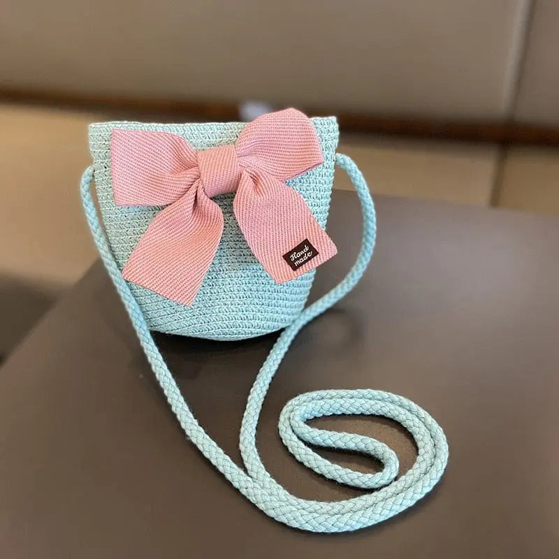 A girls' summer set featuring a light blue woven shoulder bag with a pink bow and a floral straw sun hat, perfect for kids aged 2-8, ideal for travel or beach, shown together on a dark background.