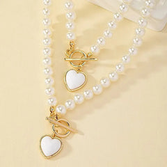 A two-piece set featuring imitation pearl necklaces with gold-tone heart pendants and toggle clasps.