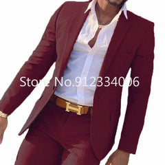 A man wears a slim-fit burgundy suit with a white button-down shirt and a tan belt.