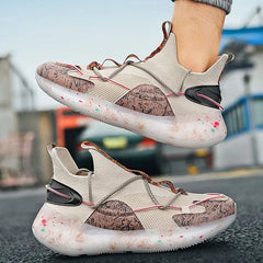 A person stands on a dark outdoor surface wearing 2022 Top Sale Fashion Sneakers—beige with brown, pink, and green accents, thick patterned soles, unique laces, breathable recycled materials, and lightweight TPU design.