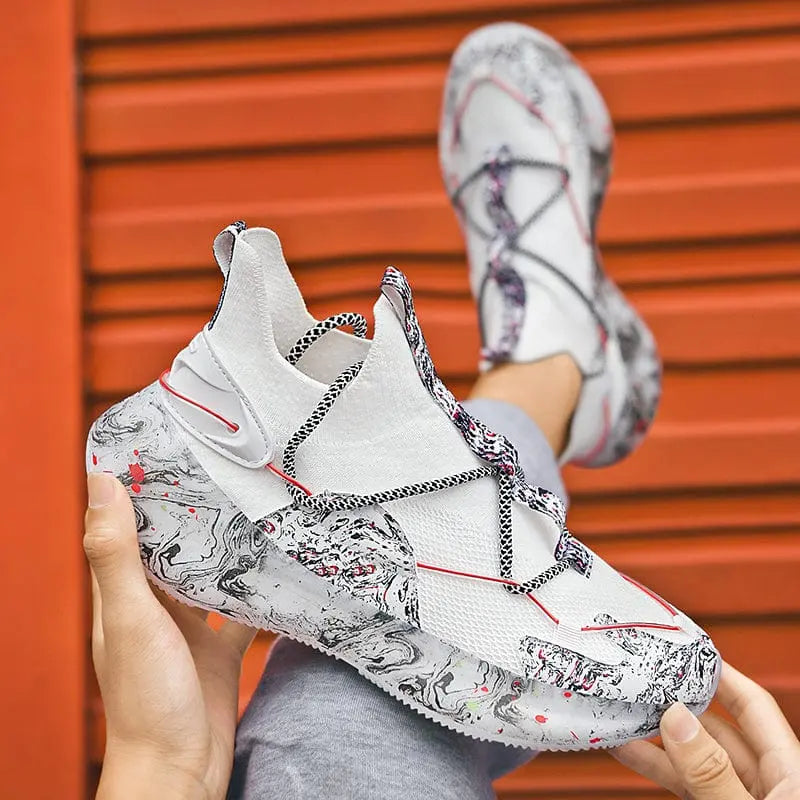 A person holds the 2022 Top Sale Fashion Sneaker—white, with a marbled gray and black sole, red accents, and black-and-white laces—while wearing the matching recycled, breathable men’s running shoe against an orange backdrop.