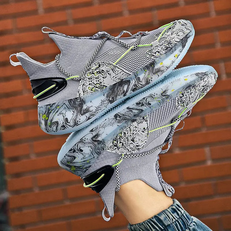 A person holds up the 2022 Top Sale Fashion Sneaker—breathable, lightweight recycled men's shoes with a marbled white, black, and green sole, mesh details, and neon green accents—against a brick wall.