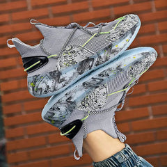 A person holds up the 2022 Top Sale Fashion Sneaker—breathable, lightweight recycled men's shoes with a marbled white, black, and green sole, mesh details, and neon green accents—against a brick wall.