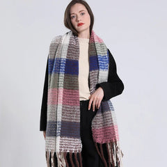 A woman wears a long, thick, multicolored plaid cashmere scarf with fringe ends.