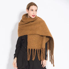 A woman wears a long, thick, brown cashmere-blend scarf with fringe detailing.