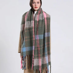 A woman wears a long, thick, olive green plaid scarf with pink and blue accents and fringe ends.