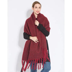 A woman wears a long, thick, burgundy plaid cashmere scarf with fringe ends.