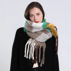 A woman wears a long, thick plaid cashmere scarf featuring green, brown, white, and yellow tones.