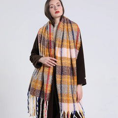 A woman wears a long, thick plaid scarf in shades of yellow, pink, brown, and blue with tassels.
