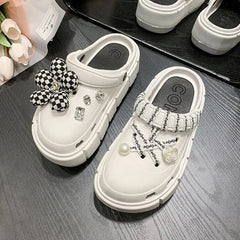 A pair of white platform clogs for women featuring decorative charms and ribbon accents.