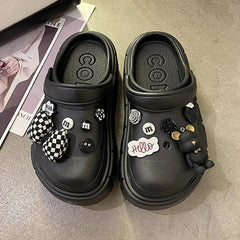 A pair of black platform clogs decorated with various charms including bows and bears.