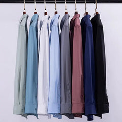 A row of long-sleeved men's dress shirts in various solid colors hanging on a rack.