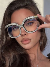 A woman wears oversized, round, anti-blue light glasses with a rhinestone-encrusted frame.