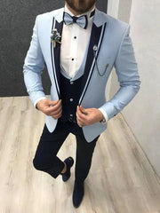 A three-piece suit featuring a light blue blazer with dark lapels, a navy vest, and navy trousers.