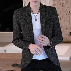A man wears a slim-fit, charcoal grey textured blazer over a white t-shirt.